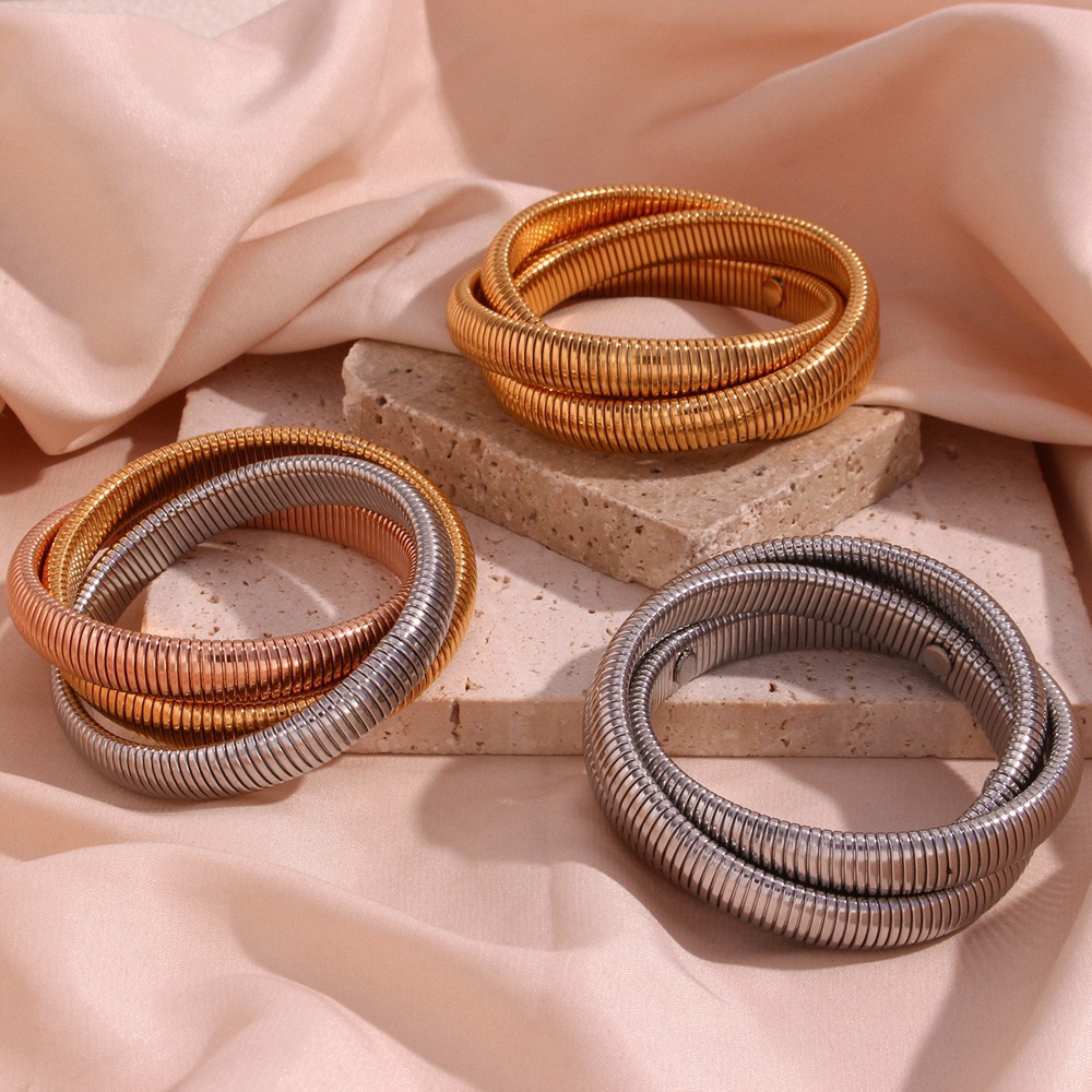 Infinity stainless steel coiled wrap bangles available in gold, silver and two-tone finishes, featuring a modern multi-layer statement design.
